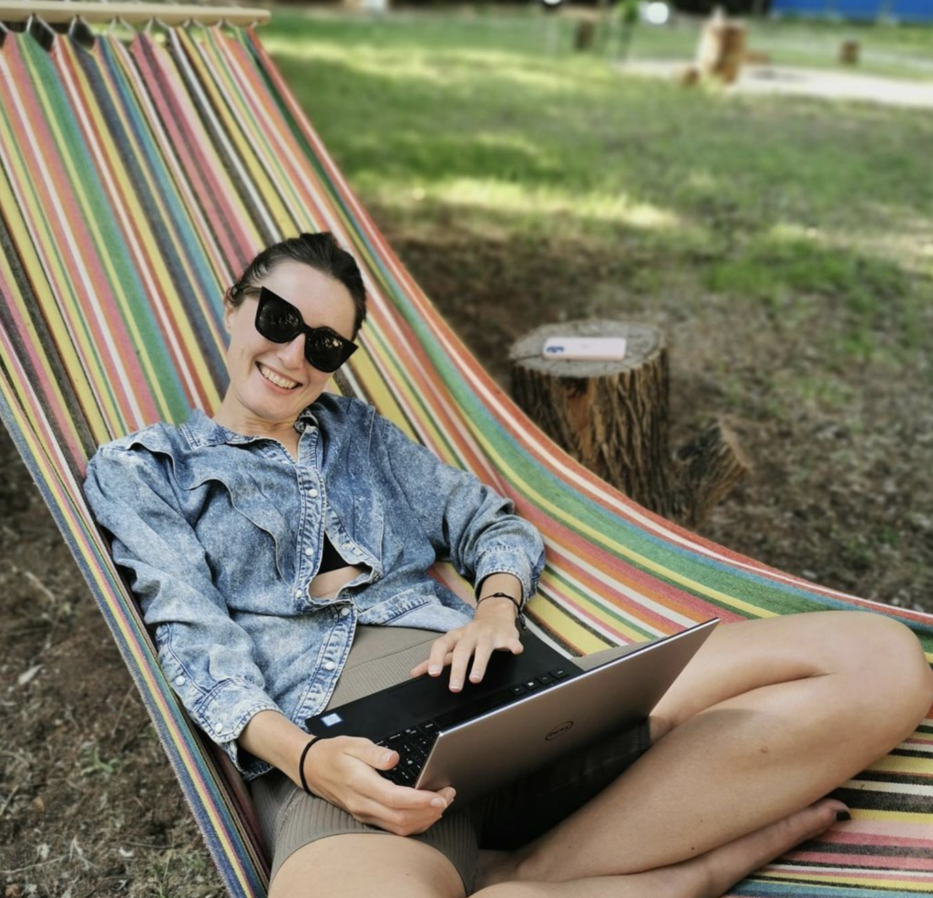 a digital nomad woman working from her laptop in a hammock smiling